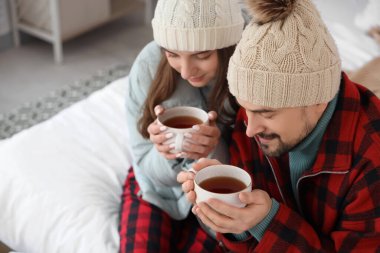 Buzlu, çay bardakları olan ve yatak odasında ısıtma sorunu olan çift, yakın plan.