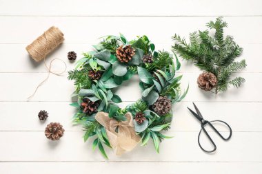 Güzel Noel ökseotu çelengi, beyaz ahşap arka planda tümsekler ve malzemeler.