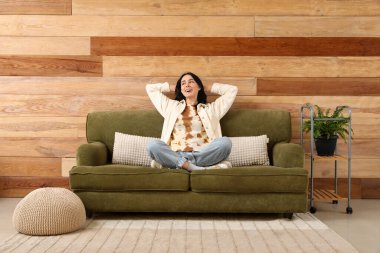 Evdeki yeşil kanepede dinlenen güzel genç bayan.