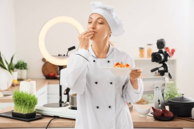 Lezzetli makarna pişirme videolarını mutfağa kaydeden olgun kadın şef.