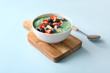 Lezzetli spirulina smoothie ve mavi arka planda böğürtlenli kase.