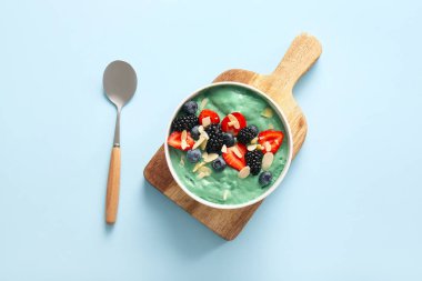 Lezzetli spirulina smoothie ve mavi arka planda böğürtlenli kase.