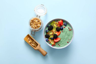 Lezzetli spirulina smoothie ve mavi arka planda bir kavanoz granola.