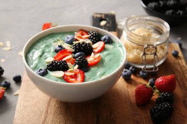 Gri grunge arka planda bir kase lezzetli spirulina smoothie, yakın plan.