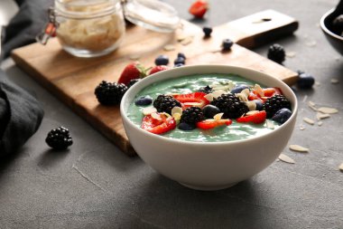 Gri grunge arka planda bir kase lezzetli spirulina smoothie, yakın plan.