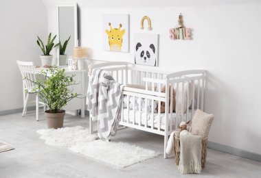 Ekoseli şık beyaz bir beşik ve çocuk odasının iç tarafındaki duvarda resimler.