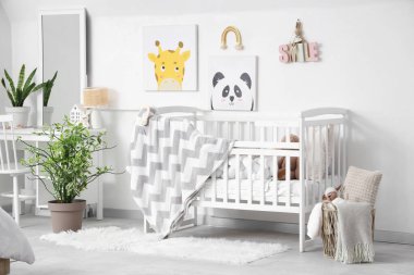 Ekoseli şık beyaz bir beşik ve çocuk odasının iç tarafındaki duvarda resimler.