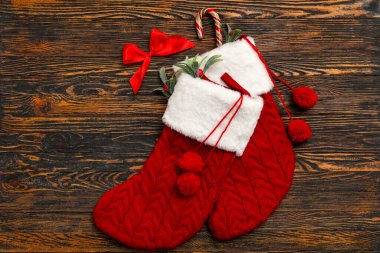 Ökseotu dallı Noel çorapları, baston şekerler ve tahta arka planda fiyonk. Üst görünüm