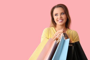 Pembe arka planda alışveriş torbaları olan güzel genç bir kadın. Kara Cuma konsepti