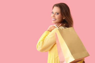 Pembe arka planda alışveriş torbaları olan güzel genç bir kadın. Kara Cuma konsepti