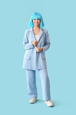 Mavi peruklu ve renkli arka planda şık giyinmiş güzel bir kadın.