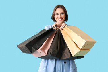 Mavi arka planda alışveriş torbaları olan güzel genç bir kadın. Kara Cuma konsepti