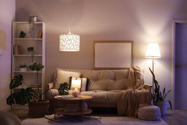 Oturma odasında rahat bir kanepe, sehpa ve akşam lambaları var.