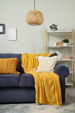 Oturma odasının içinde ekoseli ve minderli mavi kanepe.