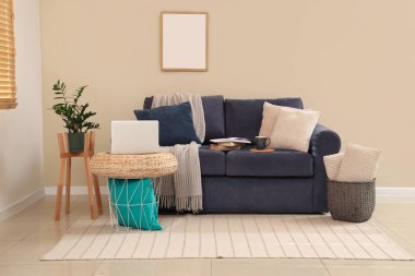 Oturma odasının iç tarafında dizüstü bilgisayarı olan rahat bir kanepe ve kahve masası.