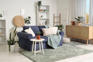 Oturma odasının içinde rahat bir kanepe ve çiçekli bir sehpa.