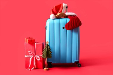 Noel Baba şapkası, çorap, hediyeler ve kırmızı arka planda Noel ağacı.
