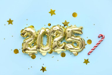 Şekil 2025 folyodan yapılma, baston şekerli balonlar ve mavi arka planda konfeti. Noel kutlaması