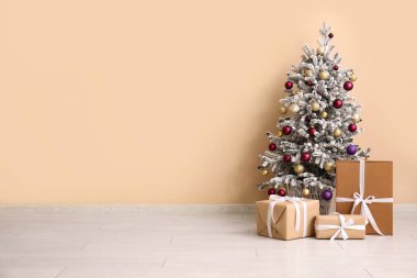 Odada bej duvarın yanında hediye kutuları olan Noel ağacı.