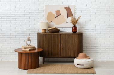 Dekorlu çekmeceler, sehpa ve beyaz tuğla duvarın yanındaki oda.