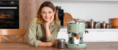 Mutfakta kahve makinesi olan genç bir kadın.
