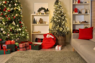Oturma odasının içinde Noel çantası ve Noel ağaçları var.