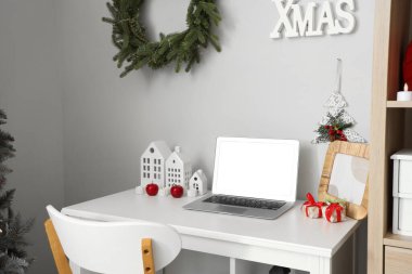 Ofisinde dizüstü bilgisayarı ve Noel dekoru olan bir işyeri