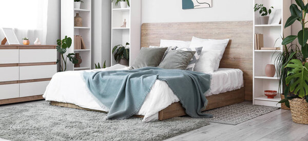 Interior of beautiful modern bedroom with houseplants