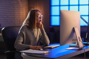 Geceleri bilgisayarla çalışan kadın programcı.