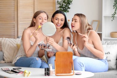 Evde makyaj yapan genç kadınlar.
