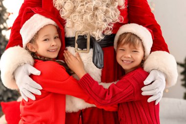 Noel arifesinde evde Noel Baba 'ya sarılan şirin çocuklar.