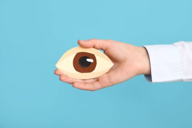 Renkli arka planda kağıt insan gözü olan kadın el, yakın plan.