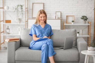 Oturma odasındaki kanepede dizüstü bilgisayarı olan kadın stajyer.