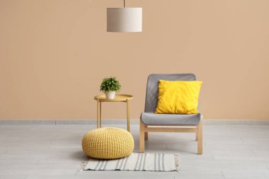 Yastıklı koltuk, puf ve bej duvarlı kahve masası.