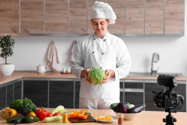 Taze sebzeli erkek şef mutfakta yemek pişirme videosu kaydediyor.