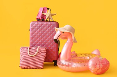 Sarı arka planda şişme yüzük, çanta ve plaj aksesuarları olan çanta.