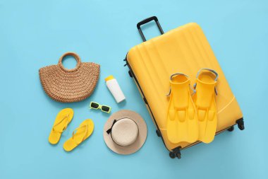 Mavi arka planda yüzgeçli bavul ve plaj aksesuarları