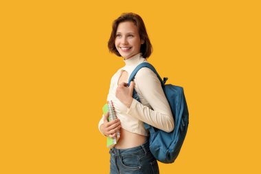 Sarı arka planda not defterleri ve sırt çantasıyla güzel bir kız öğrenci.