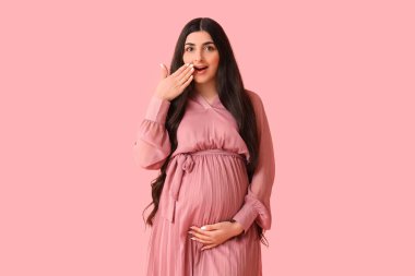 Pembe arka planda hamile bir kadın.