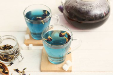 Kelebekli kavanoz bezelye çiçeği çayı ve beyaz arka planda mavi organik çay, yakın plan.