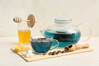 Bambu hasırı, çaydanlık, bir fincan kelebek, bezelye çiçeği çayı ve beyaz arka planda bal.