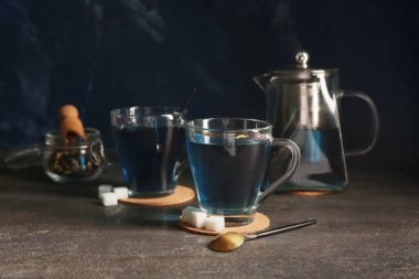 Çaydanlık ve bir fincan kelebek arkaplanda bezelye çiçeği çayı.