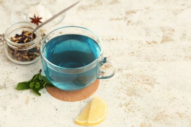 Bir fincan mavi organik çay ve arkaplanda kavanozda bezelye çiçeği çayı.