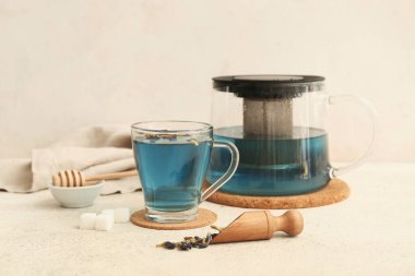 Çaydanlık ve bir fincan kelebek arkaplanda bezelye çiçeği çayı