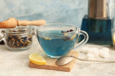 Bir fincan kelebek, bezelye çiçeği çayı ve ahşap tezgah arka planda, yakın plan