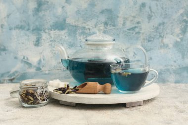 Kelebek çiçekli çay fincanı ve mavi grunge arka planda ahşap tepsi.