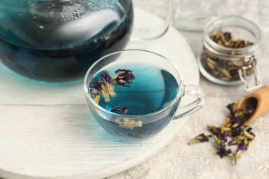 Kelebek çiçekli çay fincanı ve arkaplanda beyaz ahşap tepsi.