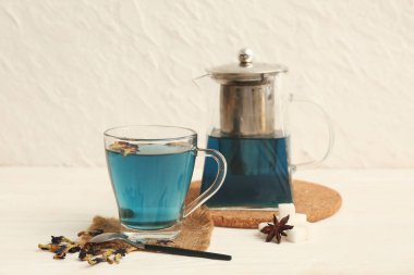 Bir fincan kelebek, bezelye çiçeği çayı ve çaydanlık masada.