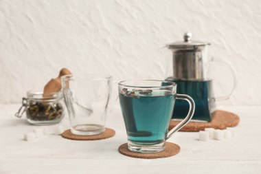 Kelebek bezelye çiçeği çayı ve fincanlar beyaz masada.