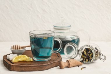 Masadaki tahta tepside bir fincan kelebek çiçeği çayı.